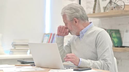 Senior Man Coughing While Working on Laptop