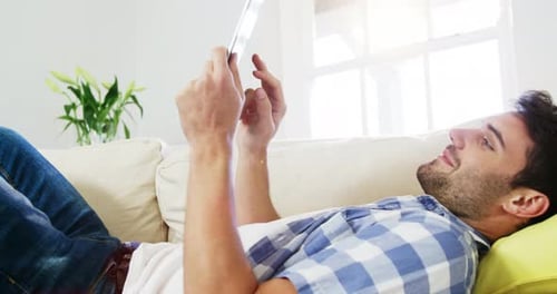 Young Adult Relaxing on Couch Using Tablet