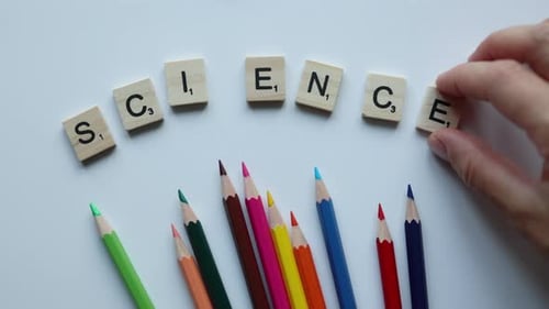 Hand Writing Word Science with Wooden Letters with Colorful Pencils on White Background
