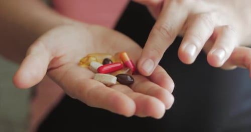 Close-up of Female Hands, Someone Pours a Bunch of Prescription Opiate Pills Into the Hand