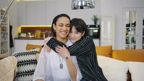 Two Young Women Hugging on a Couch