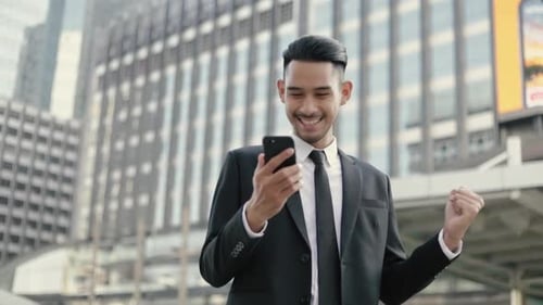 Happy Young Man Using Phone in City