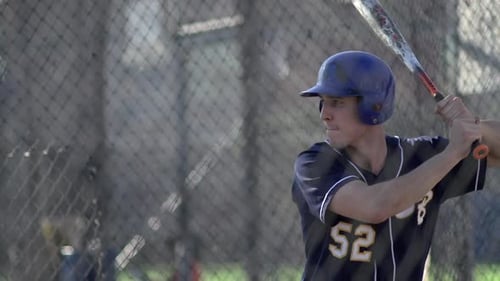 A young man practices baseball at the batting cages.