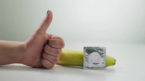 Hand Gives Thumbs Up to Safe Sex With Condom