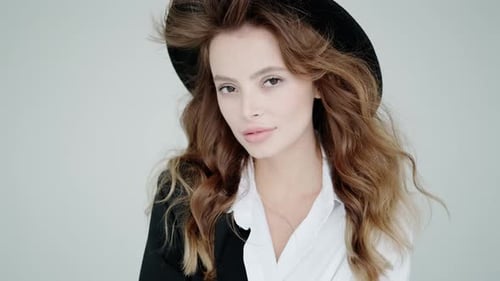 Studio Portrait of a Fashionable Young Woman Over White Background. Model in a Black Hat and Blouse