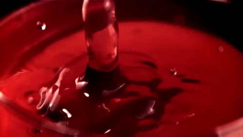 Ralenti, une goutte de vin tombe dans un verre