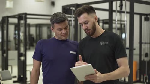 Trainer Discusses Fitness Plan with Client in Gym