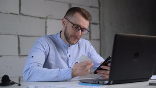 Geschäftsmann tätigt Online-Einkäufe mit einem Telefon und einer Kreditkarte