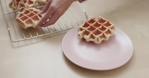 Waffles Being Placed on Plate with Chopsticks