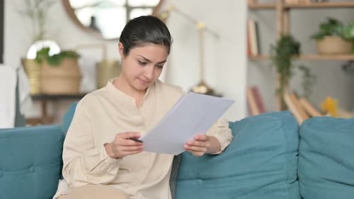 Woman Reviewing Documents on a Couch Indoors