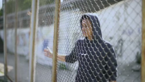 Afroamerikanischer Junge hinter Zaun, Migrantenkind von der Familie getrennt, festgenommen