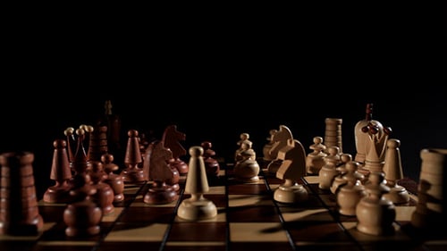 Hand Moves Chess Pieces on Dark Chessboard