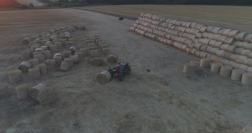 Tractor Stacking Hay Bales in Rural Field