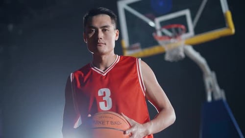 Portrait au Ralenti d'un basketteur asiatique tenant un ballon dans ses mains et sérieux