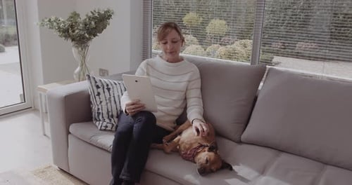 Woman Relaxing with Dog While Using Tablet