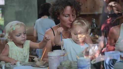 Woman and Children Painting Pottery Together at Art Studio