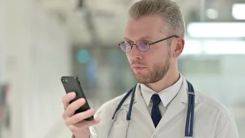 Serious Doctor Using Smartphone in Hospital Close Up