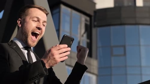 Excited Man Celebrates Good News on Mobile Phone