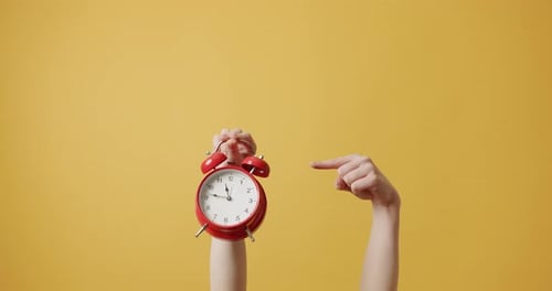 Woman Gesturing with Her Hands with Red Alarm Clock on Yellow Background