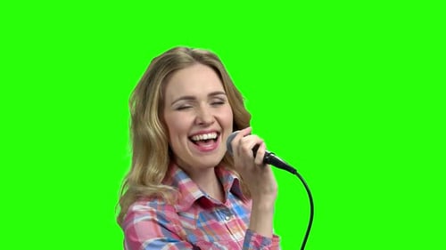 Charmante Frau singt im Mikrofon auf Greenscreen