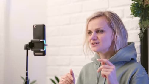 Junge Blogger-Influencerin spricht mit Followern im Live-Streaming, das auf den Smartphone-Bildschirm schaut