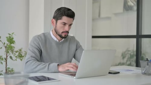 Young Man Working on Laptop in Office