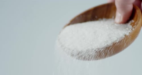 Zucker wird aus einem Holzlöffel gegossen