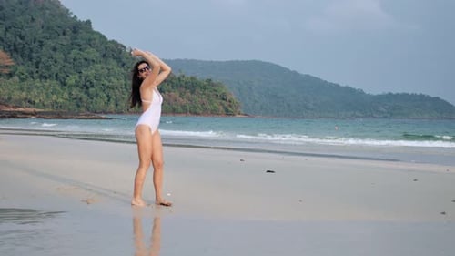 Joven hermosa mujer disfrutando de vacaciones de verano y bailando en la playa