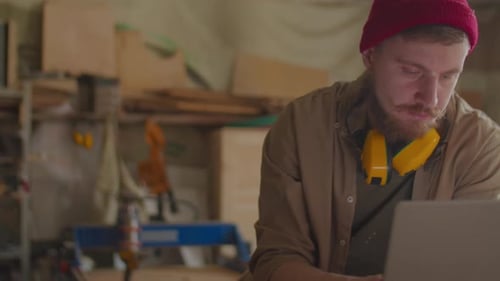 Carpenter Using Laptop in Workshop
