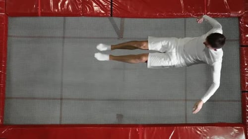 The View From the Top Gymnast Acrobat Dressed in White Performs a Somersault on the Trampoline