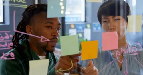 Business executives discussing over sticky note in office 4k