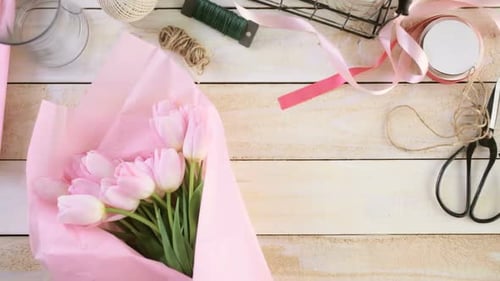 Hands Wrapping Pink Tulips Bouquet for a Gift
