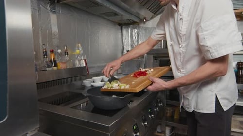 Adult Chef Adds Vegetables to Wok in Kitchen