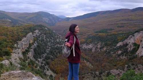 Woman with Arms Raised on Top of Mountain Looking at View