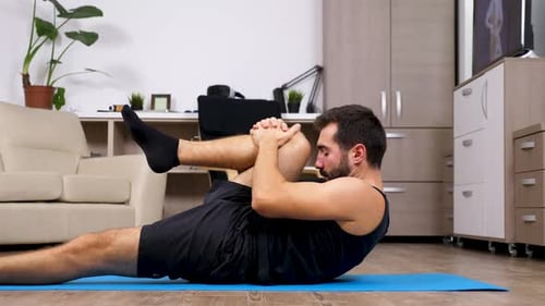 Man Stretching on Yoga Mat in Living Room
