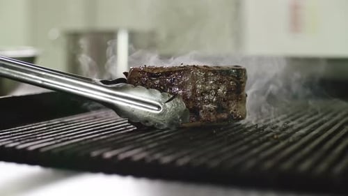 Ein Steak auf dem Grill drehen