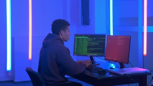 Plan moyen d'un jeune homme africain écrivant des programmes de hackers dans une pièce sombre avec des néons