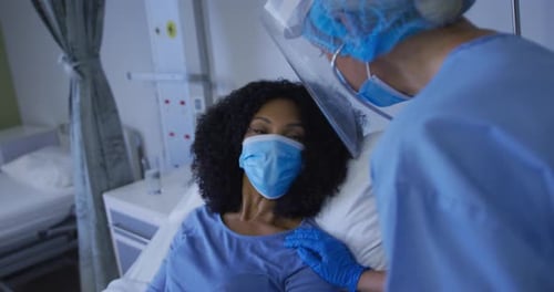 Diverse female doctor and patient wearing face masks during heart examination