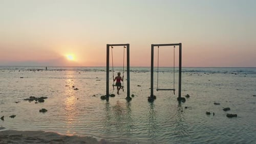 Woman Enjoying Swing on Tropical Beach at Sunrise
