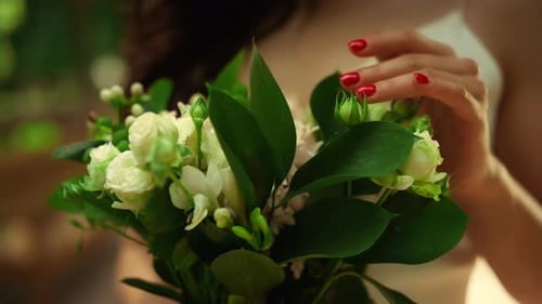 Young Woman Holding Bouquet in Park. Bride Hands Touching Flowers Outdoors