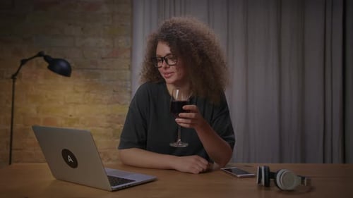 Woman with Curly Hair Video Chats While Drinking Wine