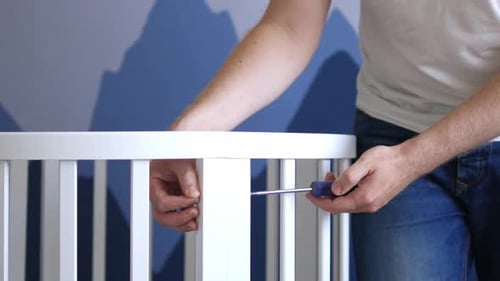 close-up man screwdriver collects a crib