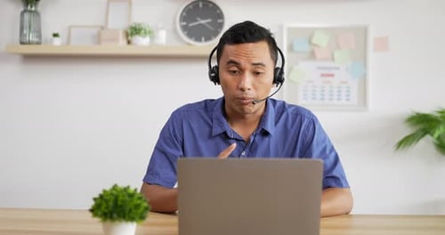 Man Communicating on Laptop with Headset in Office