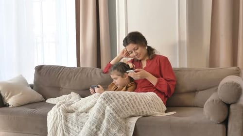 Mother and Child Using Smartphones on Couch