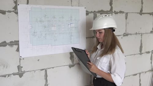 Girl engineer builder checks design drawings at a construction site.