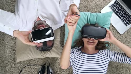 Couple Wearing VR Headsets Lying on Floor