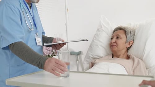 Caring Doctor Providing Water to Patient in Hospital Bed