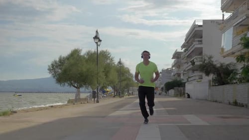 Man Running on Beachfront Path with Headphones