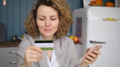 Woman Uses Phone and Credit Card Indoors