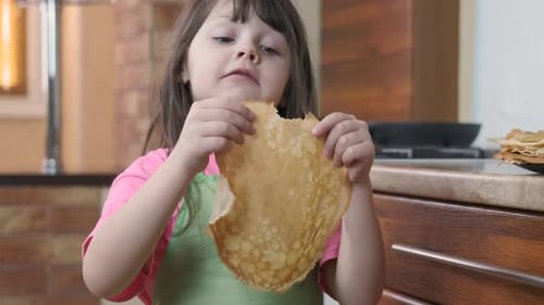 The child eats pancakes.